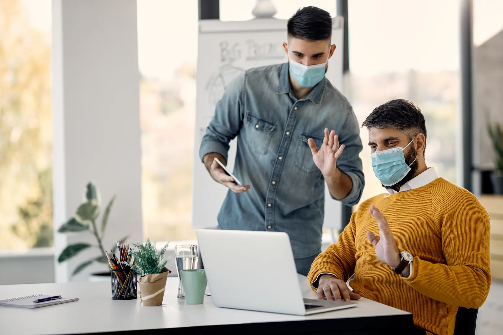 Business professionals discussing documents while wearing face masks