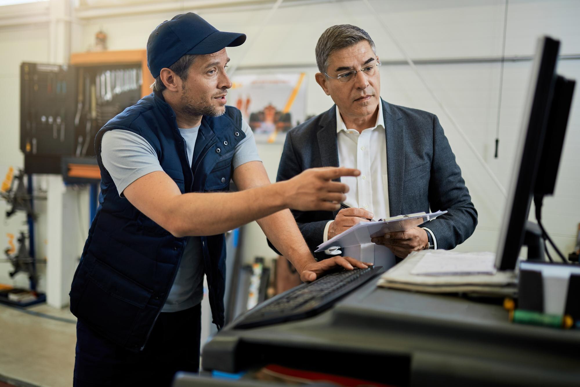 Automotive manager discussing vehicle repairs with a mechanic