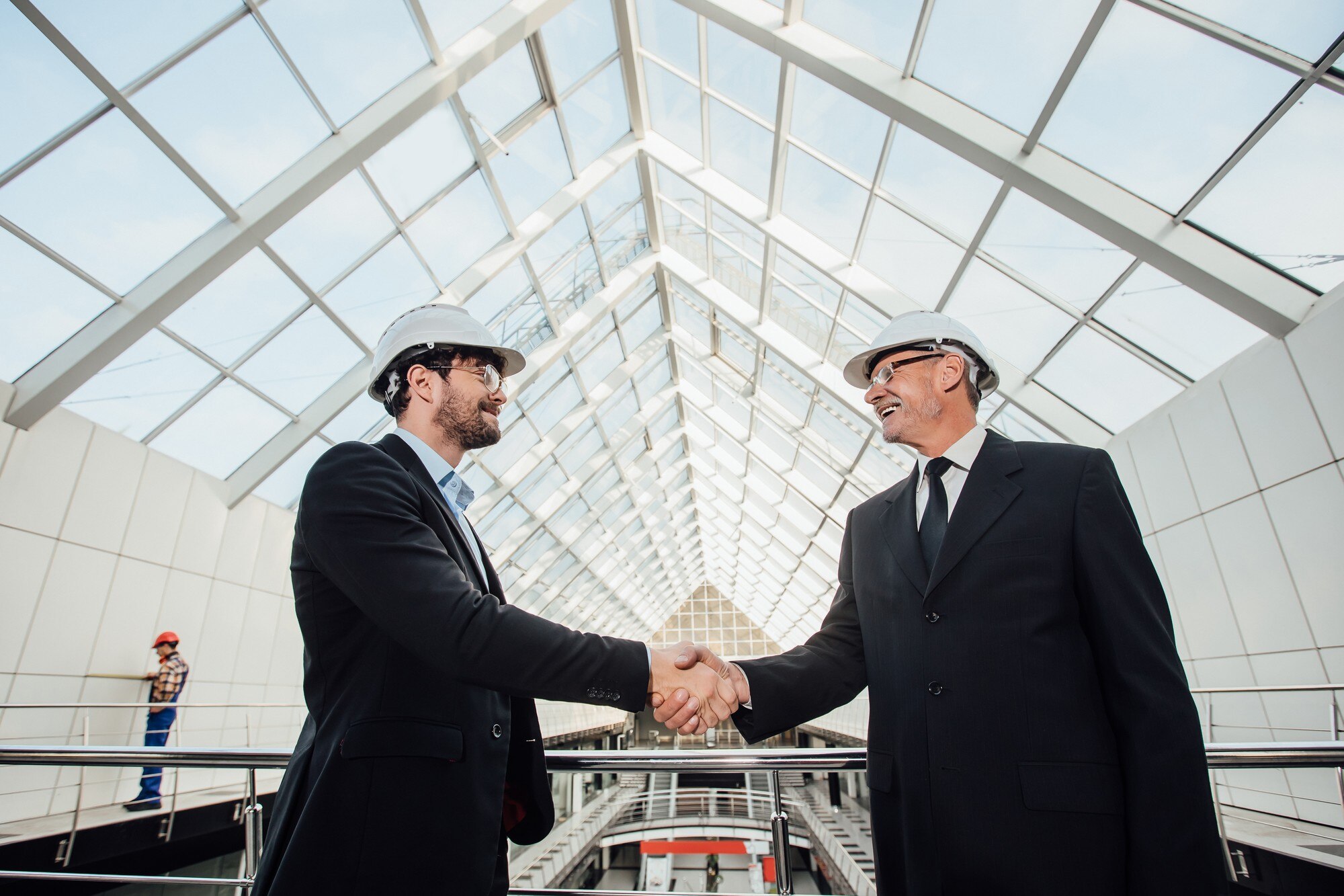 Two cheerful businessmen talking inside a modern office building